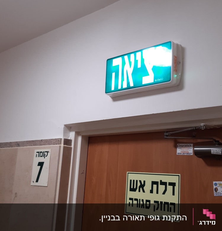 שלט יציאה מואר מעל דלת עץ